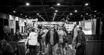 A black and white photo of people at a trade show.
