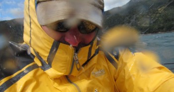 A man in a yellow rain jacket is taking a picture of the water.