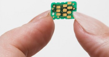 A person's hand holding a small electronic chip.