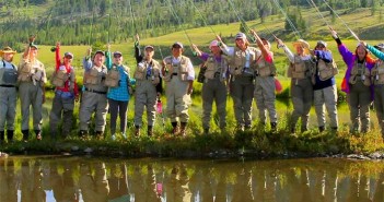 A group of people standing in front of a pond.