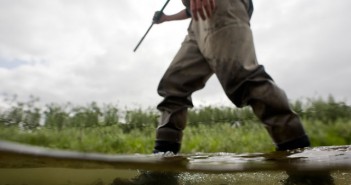 A man is standing in the water with a fishing rod.