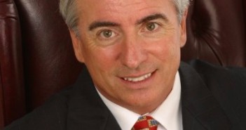 A man in a suit and tie sitting in a chair.