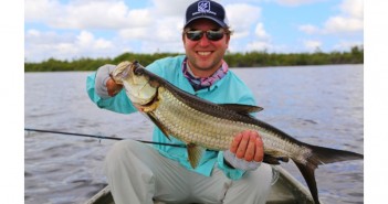 A man holding up a fish in a boat.