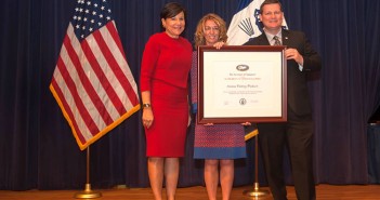 Three people standing in front of an american flag.