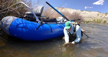 A man fishing from a raft in the river.