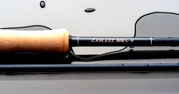 A fly rod is sitting on a surface with water on it.