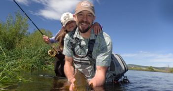 A man and a girl holding a fish in the water.