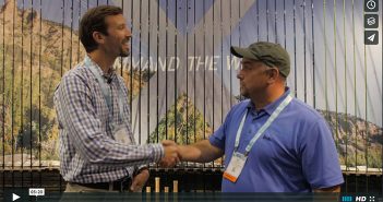Two men shaking hands in front of a banner.