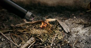 A torch is being used to light a fire in the ground.