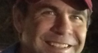 A man in a red hat smiles for the camera.