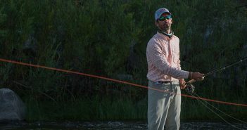 A man holding a fly rod in the water.