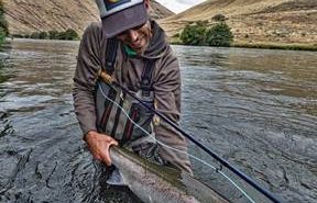 A man holding a fish in the river.