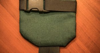 A green pouch on a wooden table.