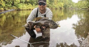 A man holding a fish in a river.