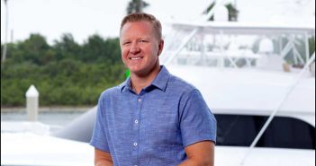 A man in a blue shirt standing on the deck of a boat.