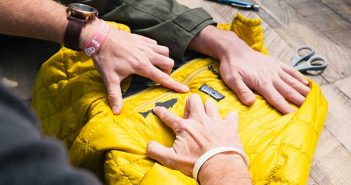 A pair of hands putting a zipper on a yellow jacket.