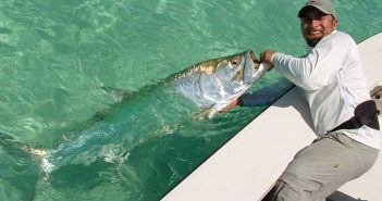 A man holding a large fish on a boat.