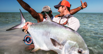 Two men holding up a large fish in the water.