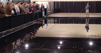 A group of people watching a man play a game of frisbee.