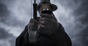 A man holding a fishing rod while holding a cell phone.