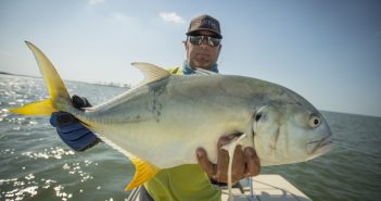A man holding up a fish on a boat.