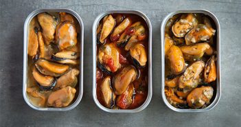 Three tins of mussels with sauce in them.