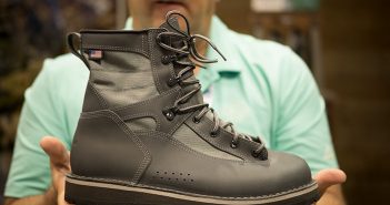 A man holding up a pair of gray hiking boots.