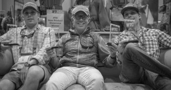 Three men sitting on a couch holding their phones.