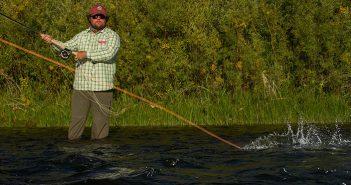 A man holding a fly rod in the water.