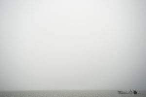 A man in a boat on a foggy day.