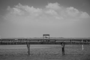 A black and white photo of a pier in the water.