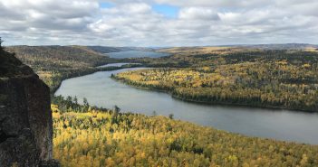 A view from a cliff overlooking a river and trees.
