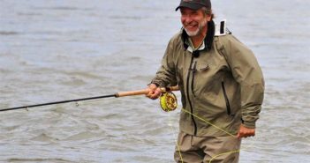 A man holding a fly rod in the water.