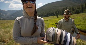 A woman holding a bunch of hats in a field.