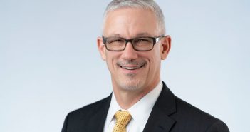 A man in a suit and tie smiles for the camera.