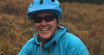 A woman wearing a blue bike helmet in a field.