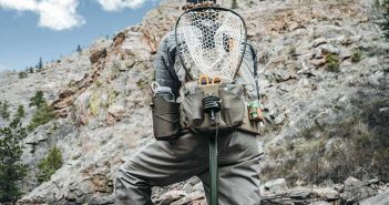 A man standing on a river with a fly fishing net.
