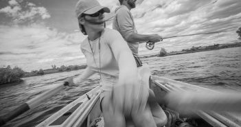 A man and woman are paddling a canoe in black and white.