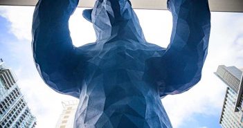 A blue sculpture of a bear in front of a building.