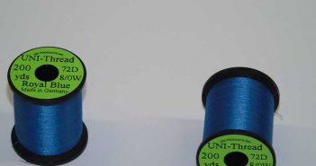 Two spools of blue thread on a white surface.