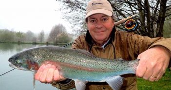 A man holding up a large rainbow trout.