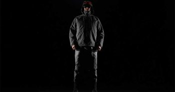 A man in a black jacket standing in front of a black background.