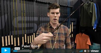 A man is holding a fishing rod in front of a wall.