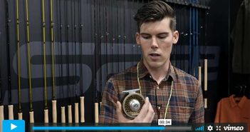 A man is holding a cell phone in front of a wall.