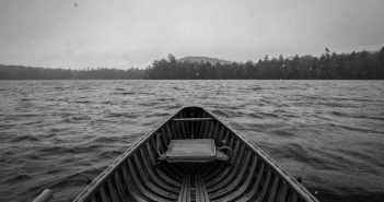 A black and white photo of a canoe on a lake.