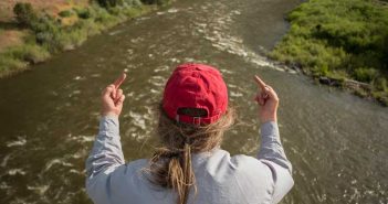 A man in a red hat is pointing at a river.
