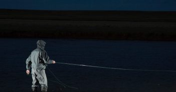 A man standing in the water with a fly rod.