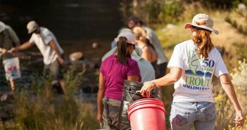 A group of people carrying buckets along a stream.
