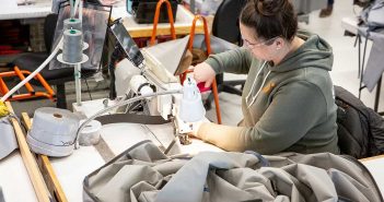 A woman working on a sewing machine in a factory.