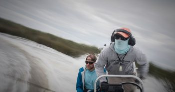 Two people on a boat fishing in the water.